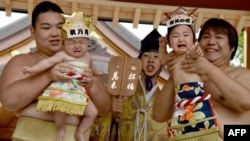 Para pegulat Sumo menggendong bayi-bayi di depan seorang juri yang mengenakan pakaian tradisional dalam sebuah acara di Kuil Kamegaike-Hachiman di Sagamihara, Prefektur Kanagawa, 14 Mei 2017. Jepang mencatat jumlah kelahiran bayi terendah sejak pencatatan kelahiran dimulai seabad lalu. (Foto:Dok) 