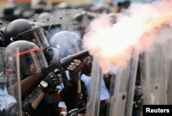 Police officer fires tear gas during a demonstration against a proposed extradition bill in Hong Kong, China June 12, 2019. REUTERS/Athit Perawongmetha