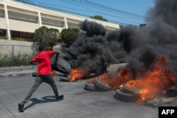 Seorang pengunjuk rasa membakar ban saat demonstrasi menyusul pengunduran diri Perdana Menteri Ariel Henry, di Port-au-Prince, Haiti, pada 12 Maret 2024. (Foto: AFP)