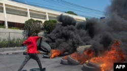 A protester burns tires during a demonstration following the resignation of its Prime Minister Ariel Henry, in Port-au-Prince, Haiti, on March 12, 2024.
