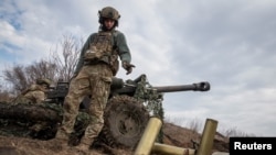 Ukrainian service members fire a howitzer M119 at a front line near Bakhmut