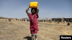 A girl carries a canister of cooking oil she received from the local charity Mona Relief at a camp for internally displaced people on the outskirts of Sana'a, Yemen March 1, 2021.