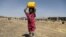 A girl carries a canister of cooking oil she received from the local charity Mona Relief at a camp for internally displaced people on the outskirts of Sana'a, Yemen March 1, 2021.