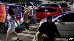 FILE - People cross a road during a rush hour traffic in Jakarta, Indonesia, March 29, 2019. Indonesia's air quality has deteriorated from among the cleanest in the world to one of the most polluted over the past two decades.