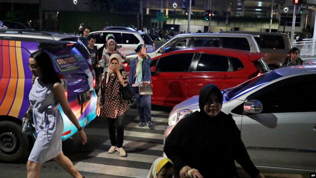 FILE - People cross a road during a rush hour traffic in Jakarta, Indonesia, March 29, 2019. Indonesia's air quality has deteriorated from among the cleanest in the world to one of the most polluted over the past two decades.
