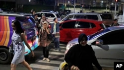 FILE - People cross a road during a rush hour traffic in Jakarta, Indonesia, March 29, 2019. Indonesia's air quality has deteriorated from among the cleanest in the world to one of the most polluted over the past two decades.