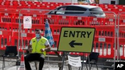 A staff member waits at the entrance to nearly empty lanes of a COVID-19 drive-thru testing facility at Twickenham stadium in London, Sept. 17, 2020. 