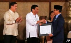 Presiden Filipina Rodrigo Duterte (tengah) dan pemimpin Front Pembebasan Islam Moro, H. Murad Ebrahim (kanan) bersalaman usai upacara penandatanganan UU khusus Wilayah Otonomi Muslim Mindanao di Istana Malacanang, Manila, Filipina, 6 Agustus 2018. (Foto: Bullit Marquez/AP Photo)