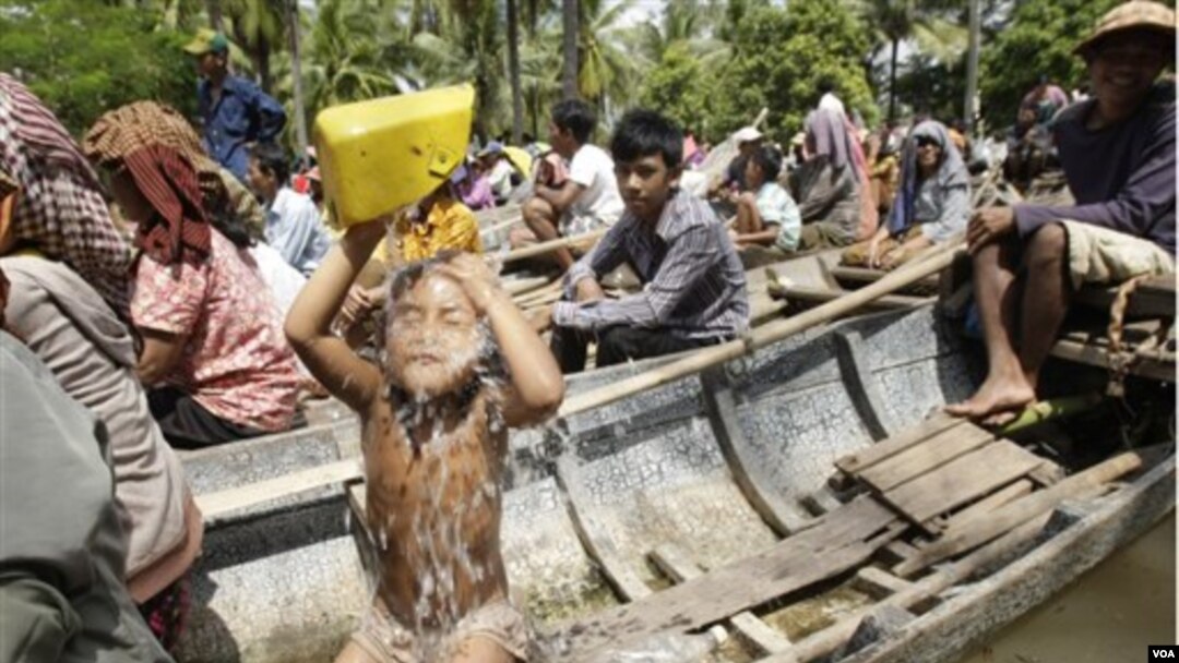 Seorang anak mandi saat keluarga dan para korban banjir yang lain antri di atas perahu untuk menerima bantuan di Prek Sussey, provinsi Kandal. Provinsi ini termasuk daerah yang paling menderita akobat bencana banjir di Kamboja.