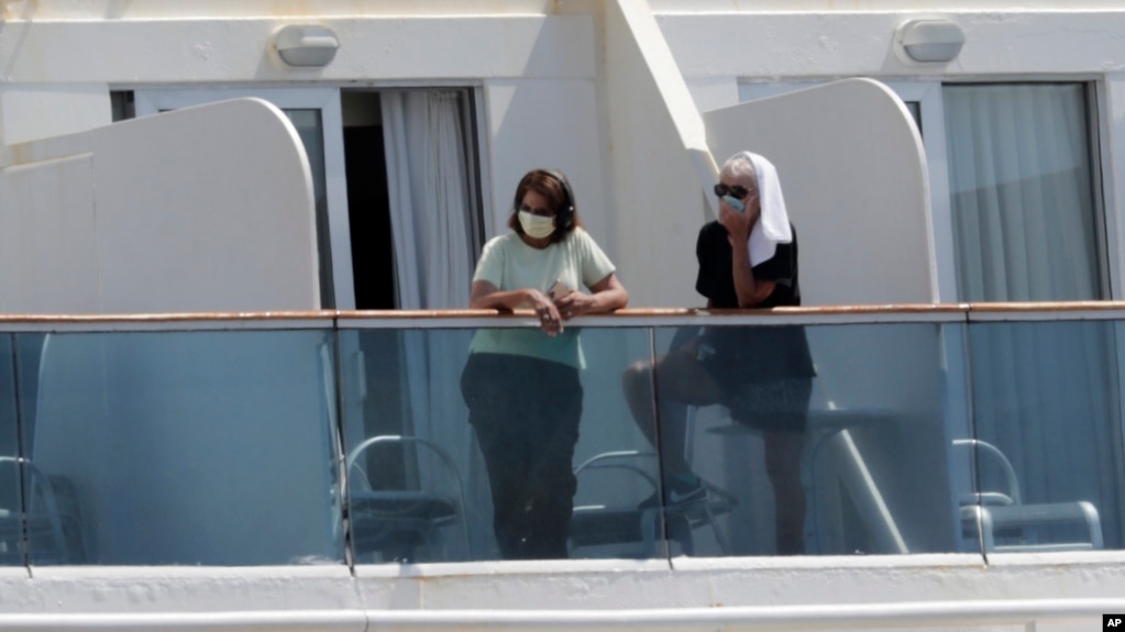 停靠在迈阿密港的珊瑚公主号游轮上的乘客戴着防护面具从阳台向外眺望。（2020年4月4日）