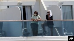 停靠在邁阿密港的珊瑚公主號遊輪上的乘客戴著防護面具從陽台向外眺望。 （2020年4月4日）