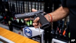 Un empleado muestra una pistola en una tienda de venta de armas de fuego en Nueva York, el 23 de junio de 2022.