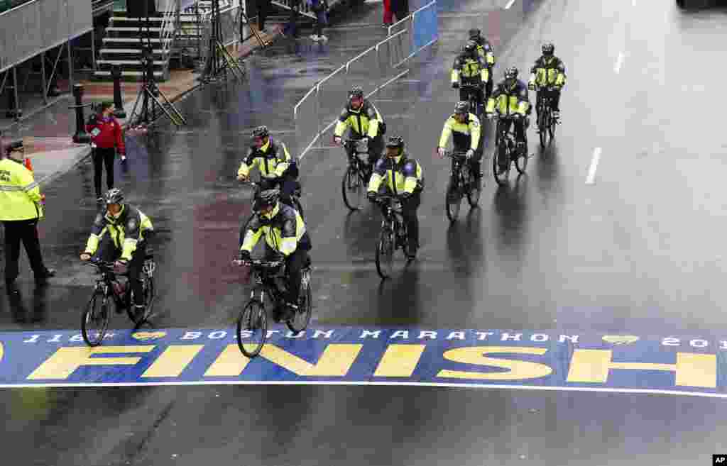 Police on bikes cycle across the Boston Marathon finish line prior to a remembrance ceremony for family members and survivors of the 2013 Boston Marathon bombings on Boylston Street, April 15, 2014.