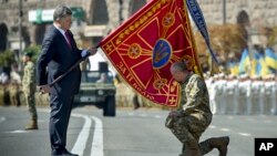 Ukraine's President Petro Poroshenko hands over a flag of a military unit on the occasion of Ukraine's Independence Day in the capital Kiev, Ukraine, Monday, Aug. 24, 2015. Speaking at the parade, President Petro Poroshenko said Ukraine would continue to increase its troop numbers in order to fend off the attacks of separatist rebels.(AP Photo/Mykola Lazarenko, Pool)