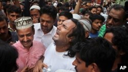 People comfort the brother, center, of famous Sufi singer Amjad Sabri, who was killed by unknown attackers, outside his residence in Karachi, Pakistan, Wednesday, June 22, 2016.