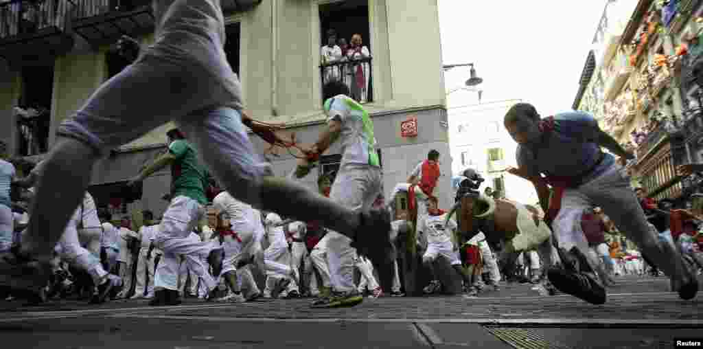 Runners sprint alongside Valdefresno fighting bulls at the Estafeta corner during the third running of the bulls of the San Fermin festival in Pamplona July 9, 2013. Two runners were treated in hospital for bruising following the run that lasted two minut