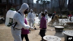 Members of a local residents group wear protective gear as they disinfect a local park as a precaution against the new coronavirus in Seoul, South Korea, Monday, March 23, 2020. 