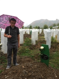 Behidin Piric, a survivor of the Srebrenica Genocide of 1995, stands next to the grave of his aunt's husband, who was killed in the massacre, while visiting the Srebrenica Memorial Center in Bosnia in 2012.