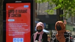 FILE - Pedestrians walk past a sign warning members of the public about a "Coronavirus variant of concern," in Hounslow, west London, Britain, June 1, 2021.