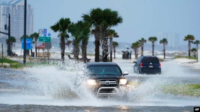 Cars drive through flood waters along route 90 as outer bands of Hurricane Ida arrive Sunday, Aug. 29, 2021, in Gulfport, Miss. (AP Photo/Steve Helber)