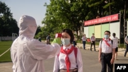 A student has her temperature taken as part of anti Covid-19 procedures before entering the Pyongyang Secondary School No. 1 in Pyongyang, North Korea, June 22, 2021. 