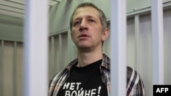 Russian journalist Roman Ivanov, wearing a T-shirt that reads "No war," stands inside a defendant's cage after being sentenced to seven years in prison for criticizing the Ukrainian offensive in social media posts, in Korolyov, Russia, on March 6, 2024.