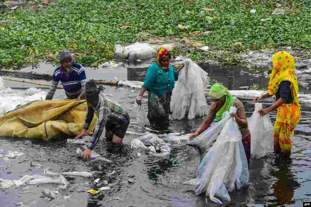 Workers scrub plastic bags used to carry industrial chemicals in the Buriganga River in Dhaka, Bangladesh.