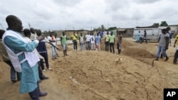 An Ivorian Red Cross worker photographs an area claimed to be a mass grave on May 4, 2011 during a mission to collect corpses in Yopougon, a district to the west of Abidjan.