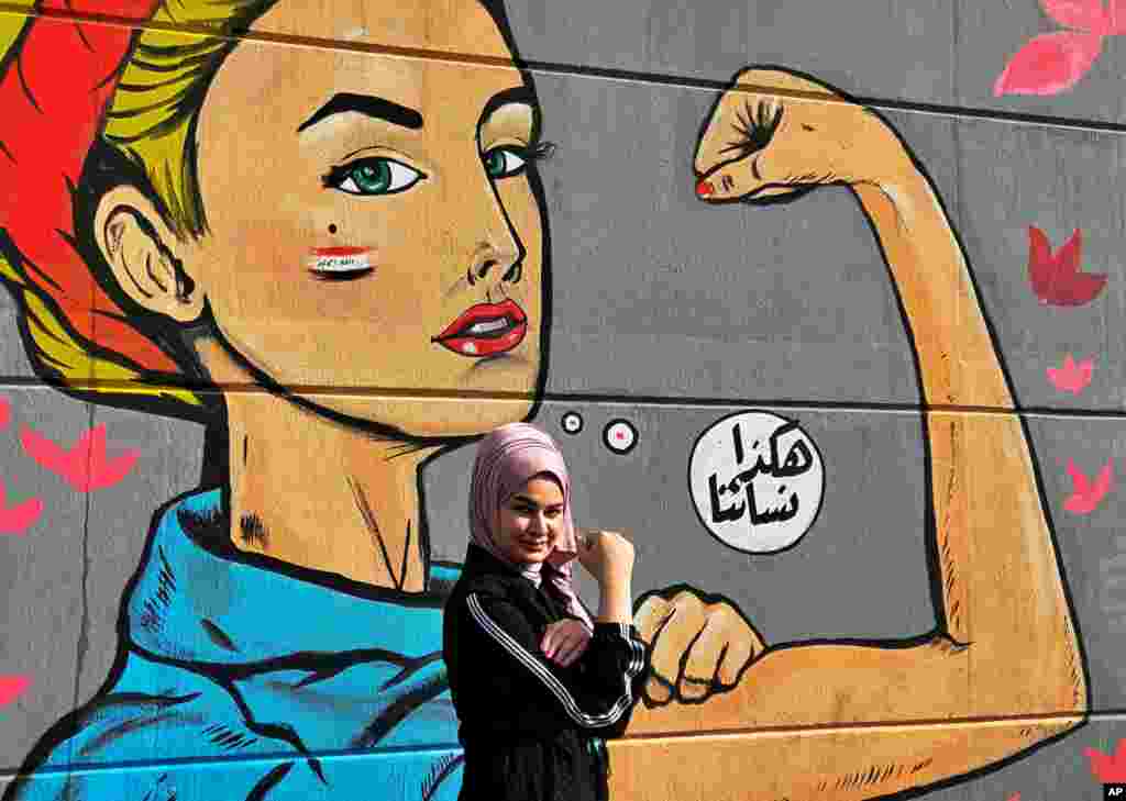 A woman poses for a picture in front of a mural with Arabic that reads, &quot;Those are our women&quot; during ongoing protests near Tahrir Square in Baghdad, Iraq.