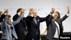 FILE - Participants react during the final plenary session at the World Climate Change Conference 2015 (COP21) at Le Bourget, near Paris, France, Dec. 12, 2015. 