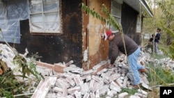 Chad Devereaux works at cleaning up the bricks that fell from three sides of his in-laws home in Sparks, Oklahoma, Nov. 6, 2011, after two earthquakes hit the area in less than 24 hours.