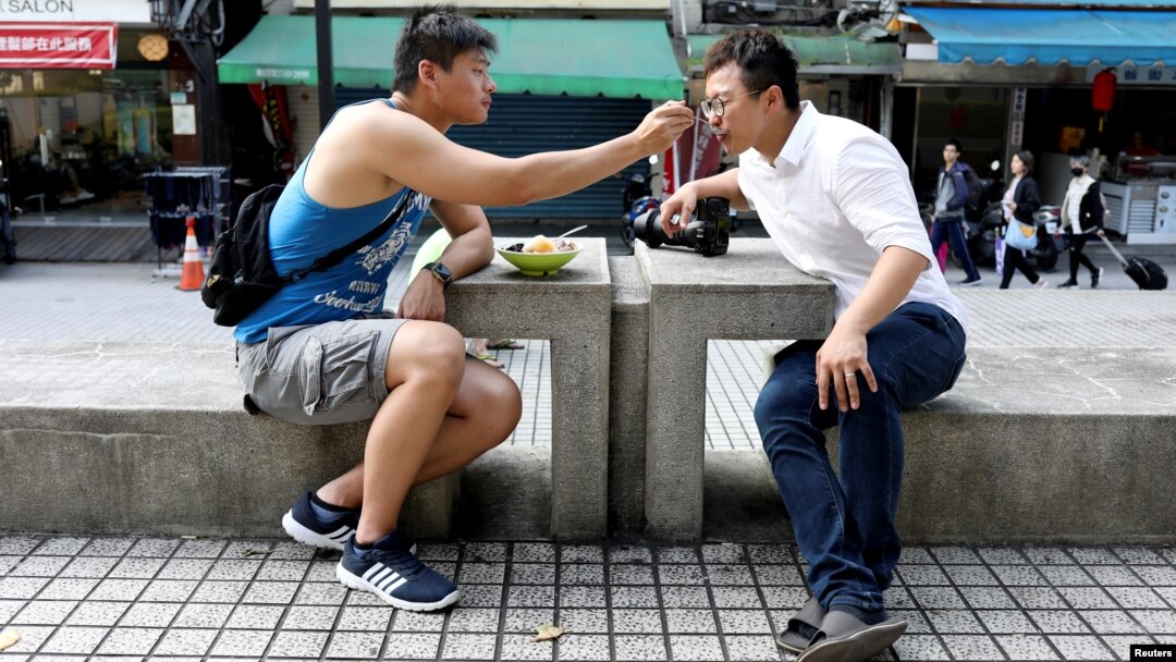 Lin Chinxuan, left, 29, feeds Austin Haung, 32, a dessert in Taipei, Taiwan, Nov. 11, 2018. Lin Chinxuan and Austin Haung are a couple and together they run Hiwow studio photographing LGBTQ couples, who they say mostly come from overseas.