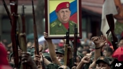 Miembros de la Milicia Nacional Revolucionaria, también llamados fuerzas bolivarianas, levantan sus armas como homenaje al presidente de Venezuela, Hugo Chávez.