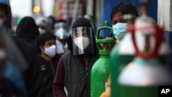 Gente espera formada con sus tanques de oxígeno vacíos para rellenarlos en una tienda en el barrio de San Juan en Lima, Perú, el lunes 3 de agosto de 2020.