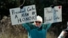 A person holds signs as the hearse containing the casket of former President Jimmy Carter, pauses at the Jimmy Carter Boyhood Farm in Archery, Ga., Jan. 4, 2025. Carter died Dec. 29 at the age of 100.