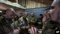 乌克兰军人在克拉希尼克村为一名阵亡战友举行的丧宴上祈祷。(2023年12月28日)
