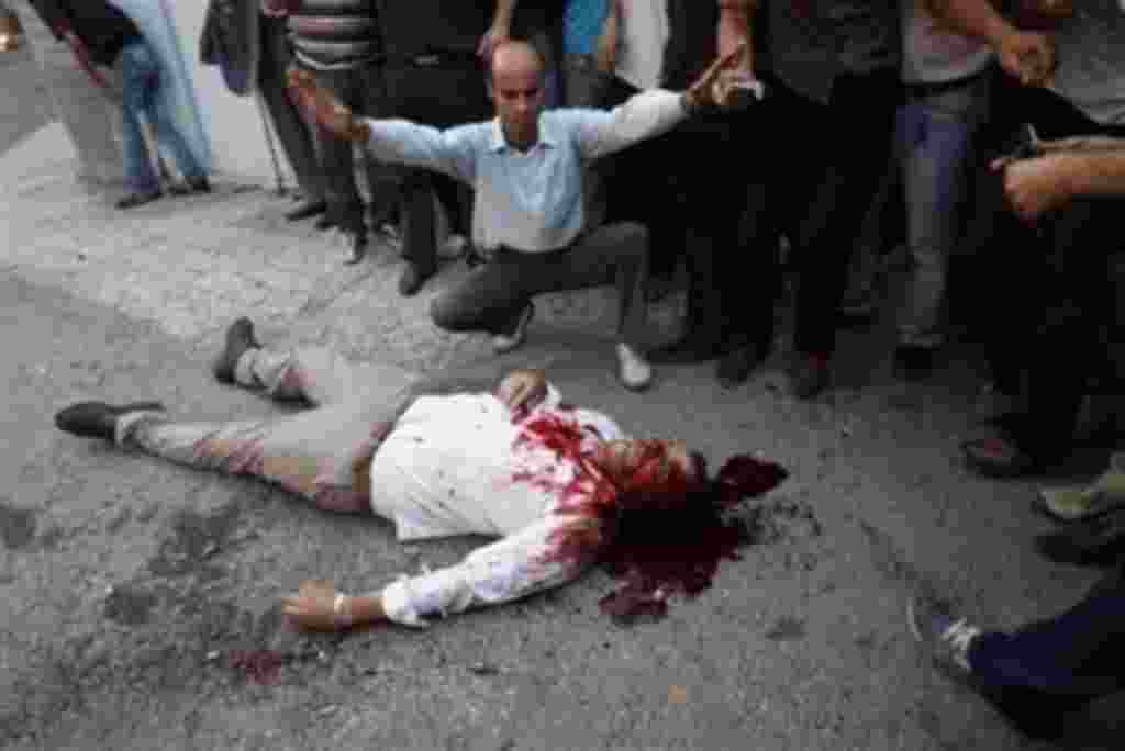 ** EDS NOTE GRAPHIC CONTENT ** Onlookers observe the body of a man allegedly shot by pro-government militia near a rally supporting leading opposition presidential candidate Mir Hossein Mousavi in Tehran, Iran, Monday, June 15, 2009. Hundreds of thousand