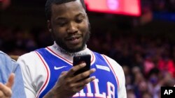 FILE - Rapper Meek Mill looks over his phone during the first half in Game 5 of a first-round NBA basketball playoff series between the Miami Heat and the Philadelphia 76ers, April 24, 2018, in Philadelphia. 