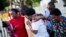 Gary and Aurelia Washington, center left and right, the son and granddaughter of Ethel Lance who died in Wednesday's shooting, leave a sidewalk memorial in front of Emanuel AME Church comforted by fellow family members, June 18, 2015, in Charleston, S.C.