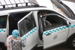 People wear masks on their faces before taking a taxi on a major thoroughfare in Casablanca, Morocco, April 6, 2021. Moroccan authorities have announced the discovery of a new local variant of the coronavirus and extended a nighttime curfew.