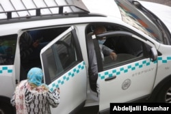 People wear masks on their faces before taking a taxi on a major thoroughfare in Casablanca, Morocco, April 6, 2021. Moroccan authorities have announced the discovery of a new local variant of the coronavirus and extended a nighttime curfew.