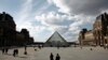 People walk by the Louvre Museum, in Paris, March 13, 2020. 