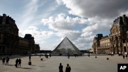 People walk by the Louvre Museum, in Paris, March 13, 2020. 