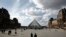 People walk by the Louvre Museum, in Paris, March 13, 2020. 