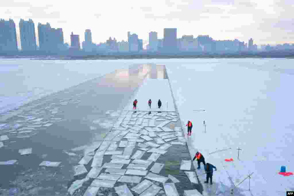 This aerial picture shows workers harvesting ice from the frozen Songhua river in preparation for the annual Harbin Ice and Snow World festival in Harbin, China&#39;s northeast Heilongjiang province, China, Dec. 17, 2024.