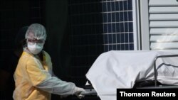 A healthcare worker wearing protective gear transports the body of a person to a refrigerated truck during the coronavirus disease (COVID-19) outbreak, at the Evandro Freire hospital in Rio de Janeiro, Brazil April 28, 2020.