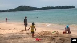 In this March 26, 2020, photo, tourists play on a beach in Phuket, Thailand. 
