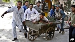 Afghans rush wounded man to treatment after a suicide car bomber strikes outside Supreme Court, Kabul, June 11, 2013.