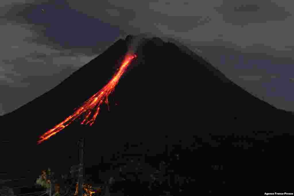 Gunung Merapi, gunung berapi paling aktif di Indonesia, tampak memuntahkan abu vulkanik dan lava dari puncaknya seperti yang terlihat dari Sleman di Yogyakarta, Senin (10/1). (Foto:&nbsp;Devi RAHMAN / AFP)