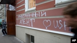 FILE - A man walks by the office of "Memorial" rights group in Moscow, Russia, Nov. 21, 2012. The building's facade is seen defaced with graffiti reading “Foreign Agent (Loves) USA.”